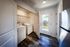 Bright laundry room featuring modern washer and dryer, elegant wood flooring, and a glass door leading to a sunlit balcony.