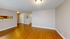 Elegant living space with sleek hardwood floors, featuring a semi-open layout and bright, neutral walls.
