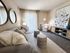 Elegant living room with plush gray sofa, stylish decor, and ample natural light through floor-to-ceiling windows.