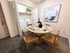 Charming dining area with a modern wooden table set for four, adorned with elegant tableware and a stylish vase. Laundry area with washer and dryer neatly tucked behind, offering convenience and efficiency. Contemporary abstract art adds a touch of sophistication.