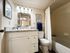 Elegant bathroom featuring sleek granite countertops, modern lighting, and a cozy bathtub with a shower curtain.