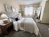 Chic bedroom featuring elegant decor with a plush bed, stylish mirror, and soft natural lighting.