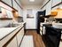 Charming kitchen featuring modern appliances, sleek countertops, and decorative shelving, perfect for culinary enthusiasts.