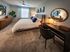 Flats at Walnut Ridge Apartments -Luxurious bedroom features a plush bed, stylish decor, and a well-lit workspace with modern accents.