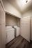 Flats at Walnut Ridge Apartments -Contemporary laundry nook with sleek washer and dryer, featuring elegant wooden flooring and ample storage space.