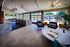 Flats at Walnut Ridge Apartments - Luxurious open-concept aqua lounge with modern furniture, elegant lighting, and expansive views of a poolside patio through large windows.