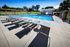 Flats at Walnut Ridge Apartments - Inviting outdoor pool area with modern loungers, surrounded by lush greenery, perfect for relaxation and leisure.