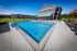 Flats at Walnut Ridge Apartments - Luxurious apartment complex featuring a sparkling blue swimming pool, surrounded by modern loungers and a pergola, set against a backdrop of elegant architecture and lush green lawns.