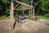 Shore Acres Apartments in Indianapolis, IN - Elegant outdoor kitchen with modern grill under a stylish wooden pergola, surrounded by lush greenery and paved stone patio.