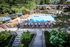 Shore Acres Apartments in Indianapolis, IN - Charming apartment complex featuring a sparkling outdoor pool with elegant lounge chairs, surrounded by lush greenery and cozy patio umbrellas, perfect for relaxation.