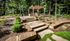 Shore Acres Apartments in Indianapolis, IN - Charming outdoor area with a stone path leading to a pergola, surrounded by lush greenery and manicured landscaping.