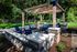 Shore Acres Apartments in Indianapolis, IN - Charming outdoor patio featuring cozy seating under a stylish wooden pergola, surrounded by lush greenery.