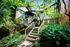 Shore Acres Apartments in Indianapolis, IN - Charming apartment entrance nestled in lush greenery, featuring elegant brickwork and inviting stairway.