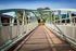 Shore Acres Apartments in Indianapolis, IN - Charming pedestrian bridge with mint-green railings leading to a serene park setting, perfect for relaxing strolls.