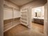 Shore Acres Apartments in Indianapolis, IN - Spacious walk-in closet with open shelving leading to a modern bathroom with elegant double vanity.
