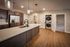 Shore Acres Apartments in Indianapolis, IN - Modern kitchen with elegant wood flooring, sleek cabinetry, stainless steel fridge, and integrated laundry space.