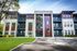 Shore Acres Apartments in Indianapolis, IN - Modern apartment building with sleek red and white exterior, surrounded by lush greenery and ample parking spaces.