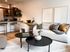 Modern open-concept living space featuring elegant decor, cozy sofa, stylish coffee tables, and a chic kitchen bar area with contemporary seating.