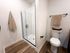 Elegant modern bathroom with a sleek glass shower, stylish subway tiles, and warm wooden flooring, exuding a spa-like ambiance.