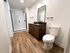 Modern bathroom with elegant wooden flooring, sleek vanity, and spacious glass shower. Perfect blend of style and functionality.