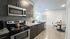 Contemporary kitchen with dark cabinetry, stainless steel appliances, and elegant lighting in an open-plan space.