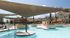 Inviting pool area with modern shade structures and lush greenery at a luxury apartment complex.
