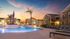 Stylish apartment complex featuring a serene pool area with palm trees at sunset.