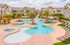 Inviting apartment complex with a stunning resort-style pool, surrounded by palm trees and comfortable lounge chairs.