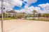 Inviting apartment complex featuring a sand volleyball court and sparkling pool under a bright blue sky.