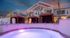 Elegant apartment complex with pool and cabanas under a colorful sunset sky.