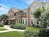 Beautiful suburban apartment with stone and siding exterior surrounded by lush greenery and well-kept lawns.