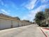 Beautiful suburban street with garages and lush greenery under a clear blue sky.