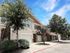 Beautiful row of townhomes with garage access, surrounded by lush greenery and trees under a clear blue sky.