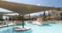 Stunning outdoor pool area with modern sunshades, surrounded by lush landscaping and stylish apartment buildings.