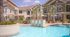 Luxurious apartment complex with landscaped pool area, palm trees, and modern architecture.