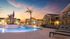 Elegant apartment complex with a serene pool area and modern architecture at sunset.