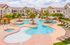 Inviting outdoor pool area surrounded by lush palm trees and elegant lounge chairs at a modern residential complex.