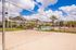 Sunny apartment complex featuring a volleyball court, pool, and lush landscaping.
