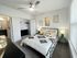 Bright and chic bedroom with modern decor, featuring an inviting bed, stylish artwork, and large windows.