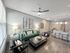 Inviting open-concept living room with modern furniture, a cozy green sofa, and a stylish kitchen island with bar stools.