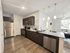 Modern kitchen with stainless steel appliances and open-plan living area featuring sleek design and natural lighting.