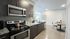 Modern kitchen with sleek appliances and stylish dining area, featuring a granite countertop and elegant lighting.
