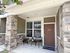 Inviting entrance of an apartment with a cozy seating area and stylish brick facade.