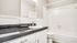 Bright and modern bathroom featuring sleek black granite countertops, white cabinetry, and a pristine shower-tub combo.