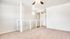 Bright, open loft space with plush carpet, modern ceiling fan, and sleek white railing, perfect for a cozy living area.