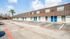 Inviting apartment complex with modern blue doors and ample parking on a sunny day.