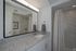 Elegant bathroom with granite countertops, large mirror, and modern shower in a stylish apartment.