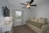 Cozy bedroom with natural light, featuring a stylish daybed and modern ceiling fan beside a window with serene outdoor views.