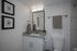 Elegant bathroom featuring a granite countertop, sleek white vanity, modern fixtures, and subtle decor with framed art and matching hand towels.