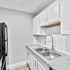 Modern kitchen with sleek white cabinetry, glossy countertops, and a stainless steel double sink, perfect for stylish culinary experiences.